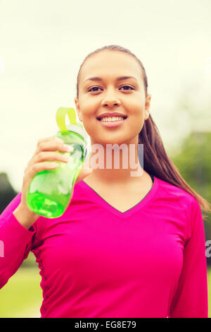 Donna sorridente di bere dalla bottiglia Foto Stock