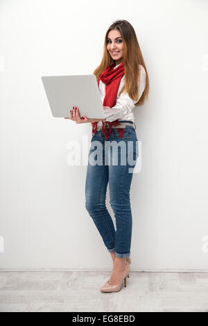 Lunghezza completa il ritratto di una donna sorridente con notebook Foto Stock