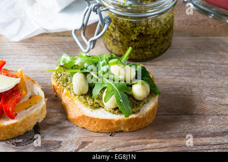 Bruschetta con fagioli e rucola, funghi, formaggi di capra su una tavola di legno Foto Stock