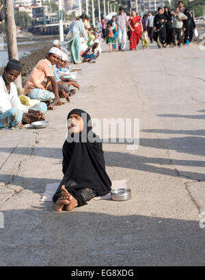 Mendicanti accumulato sulla causeway al Haji Ali moschea e Dargah , Mahalaxmi , Mumbai. Foto Stock