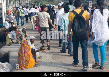 Mendicanti accumulato sulla causeway al Haji Ali moschea e Dargah , Mahalaxmi , Mumbai. Foto Stock