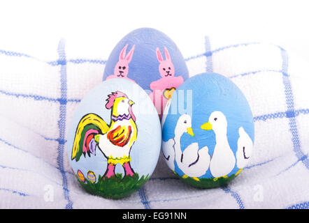Dipinto a mano le uova di Pasqua in colori luminosi con la Rooster, anatre e conigli sulla parte superiore di un asciugamano morbido Foto Stock