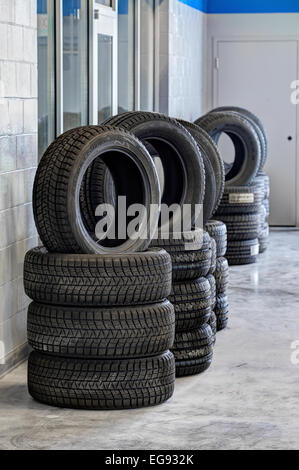 Pile di pneumatici con battistrada per varie condizioni di guida, in vendita in un garage per uso automobilistico Foto Stock