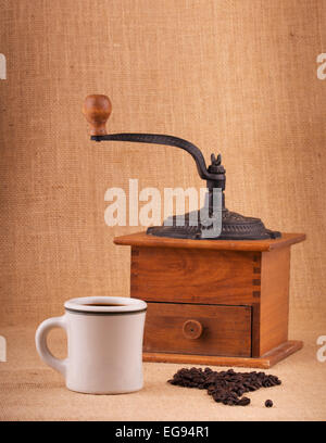 Tazza di caffè e fagioli su tela, con il vecchio macinino sullo sfondo, con lievi vignette Foto Stock