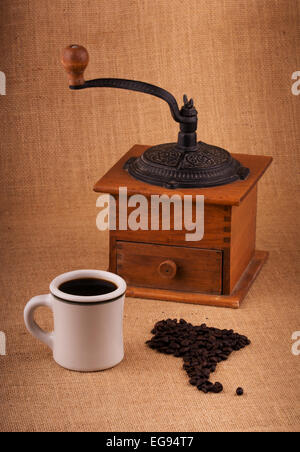 Tazza di caffè e fagioli nella forma del Sud America, con una smerigliatrice su sfondo, con lieve vignette Foto Stock