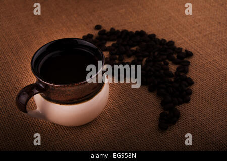 Tazza di caffè con i chicchi di caffè in un sacco di tela, dai toni caldi immagine con vignette Foto Stock