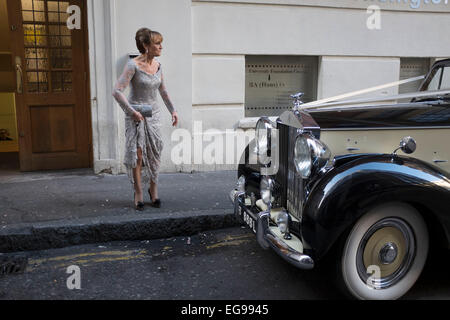 Sposa arriva per il suo matrimonio in un'annata Rolls Royce, facendo il suo ingresso attraverso il " merci " Ingresso al Connaught camere nel centro di Londra, Regno Unito. Per un tale bene per fare wedding questa sporca back street, che normalmente è usato come un "angolo mokers' fornisce un enorme contratto per la sposa nel suo bianco Abito in raso e gli ospiti nei loro abiti costosi. Sembravano tutti molto felici di essere in arrivo attraverso lo sportello posteriore anche se, come l'atmosfera era uno di risate e sorrisi. Foto Stock