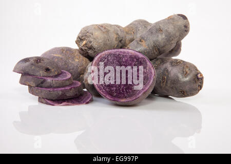 Affettato e tutta la porpora patate Vitelotte. Isolato su sfondo bianco Foto Stock