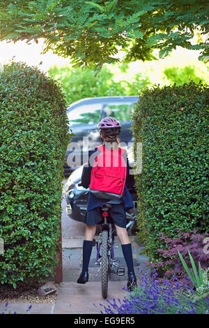 Ragazza giovane (12-13) andando a scuola in bici Foto Stock