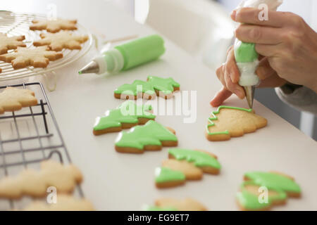 Donna decorare i biscotti con colore verde ghiaccio Foto Stock