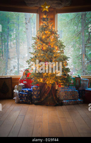 Avvolto doni sotto l'accensione di un albero di Natale Foto Stock