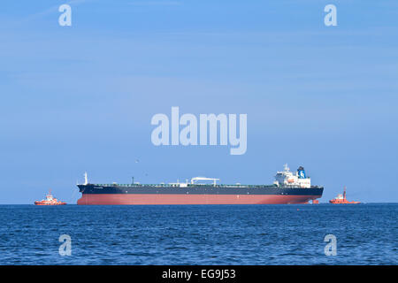 Due barche rimorchiatore si stanno muovendo la nave dal porto di mare. Foto Stock