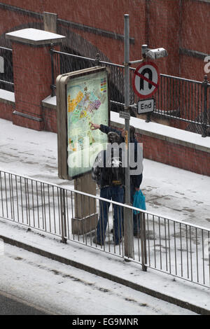 2 persone consultare una mappa, mentre si tenta di trovare la loro strada di casa sulla neve nel centro città di Manchester. Foto Stock