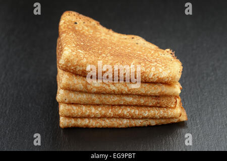 Crespelle sottili o blinis piegato in triangoli sulla scheda di ardesia Foto Stock