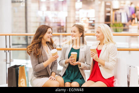 Giovani donne con le borse della spesa e caffè in mall Foto Stock