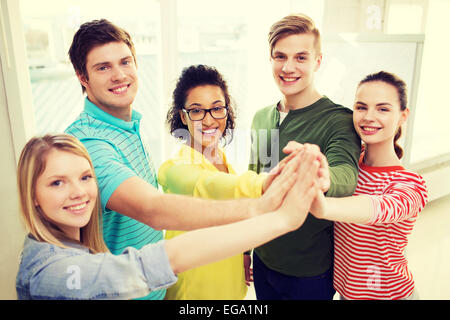 Cinque studenti sorridente dando alta cinque a scuola Foto Stock