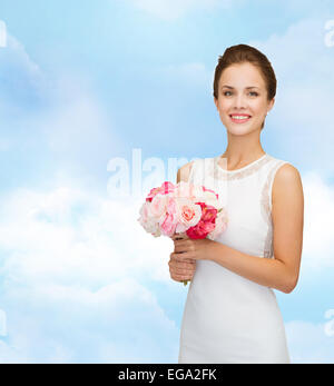 Donna sorridente in abito bianco con bouquet di rose Foto Stock