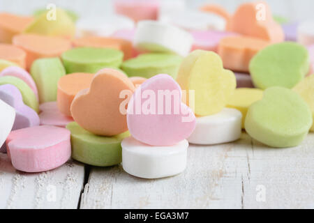 Primo piano di un gruppo di caramelle in colori pastello di San Valentino cuori su un rustico di legno bianco tavola. Formato orizzontale. Foto Stock