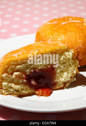 Ciambella sulla piastra tagliata a metà con marmellata che colava Foto Stock