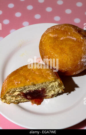 Ciambella sulla piastra tagliata a metà con marmellata che colava Foto Stock