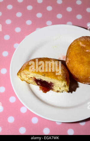 Ciambella sulla piastra tagliata a metà con marmellata che colava Foto Stock