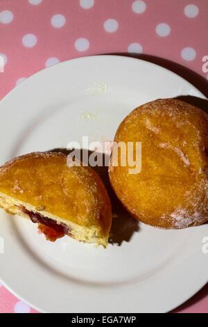 Ciambella sulla piastra tagliata a metà con marmellata che colava Foto Stock