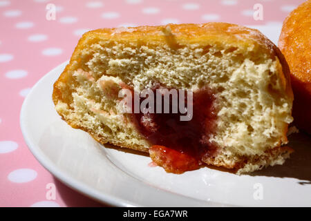 Ciambella sulla piastra tagliata a metà con marmellata che colava Foto Stock