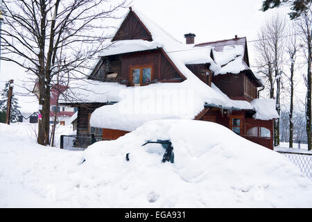 Casa e Auto sotto la neve nel villaggio di montagna il polacco Foto Stock