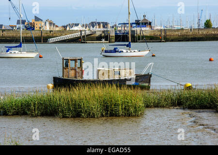Piccola barca sul fiume Medway e Chatham Maritime Marina in background, Upnor, Kent, England, Regno Unito Foto Stock