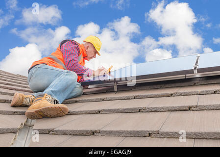 Lavoratore esperto controllo di pannelli solari sul tetto della casa Foto Stock