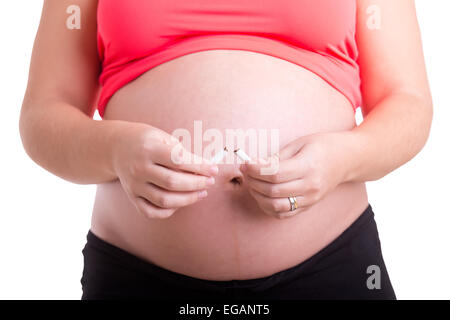 Donna incinta rompendo una sigaretta isolato in bianco Foto Stock