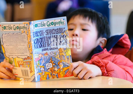 Un giovane ragazzo giapponese legge un libro sui terremoti a pochi giorni dopo il disastro Fukushima Foto Stock