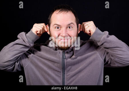 Giovane uomo che fa una faccia buffa isolato su nero Foto Stock