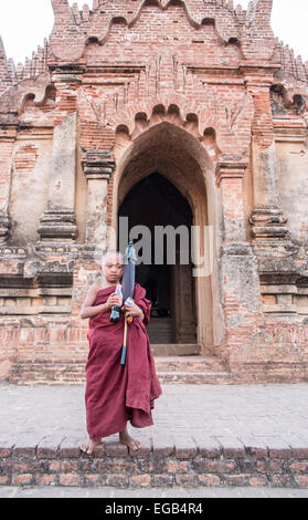 Giovane buddista monaco novizio con bottiglia di coca cola coke e ombrello,al tempio pagano in,Bagan,Birmania, Myanmar. Foto Stock