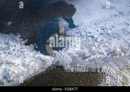 Handicap solo simbolo di parcheggio su terreni innevati spazio parcheggio. Foto Stock