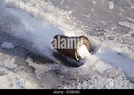 Carta monouso tazza di caffè sulla strada congelati nella neve Foto Stock