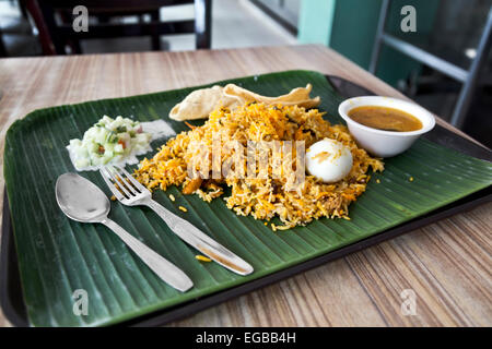 Vassoio di pollo biryani misti piatto di riso con spezie uovo dhal verdure servita sulla foglia di banano nel ristorante indiano, Singapore Foto Stock