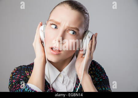 La ragazza con gli auricolari che esprimono le emozioni negative Foto Stock