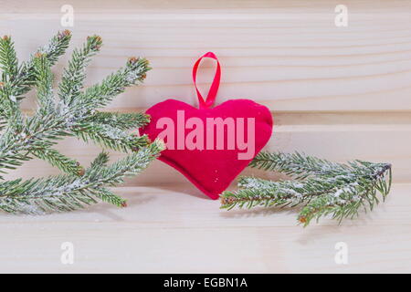 Cuore e di Abete rami ricoperti di neve su una superficie in legno Foto Stock