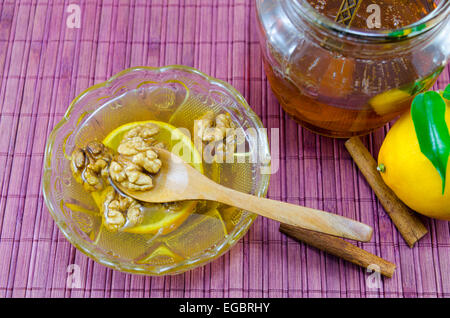 Noci e miele cannella in un recipiente su un tavolo di legno Foto Stock