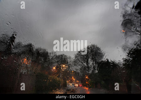 Triste noioso umido crepuscolo vista attraverso il parabrezza della vettura quando scende la notte e lo skyline di casa diventa illuminato con illuminazione al tungsteno Foto Stock