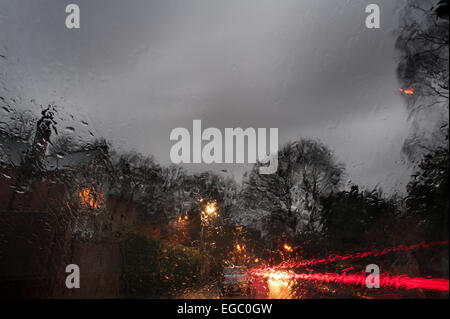 Triste noioso umido crepuscolo vista attraverso il parabrezza della vettura quando scende la notte e lo skyline di casa diventa illuminato con illuminazione al tungsteno Foto Stock