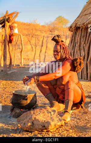 Una donna Himba rendendo il cibo. Foto Stock