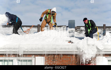 Lexington, MA, Stati Uniti d'America, 21 febbraio, 2015. Operai pulizia di neve dal tetto di una delle tre storia edificio di appartamenti in Lexington, MA, prima di un'altra neve e ghiaccio storm hits Massachusetts orientale. Credito: Chuck Nacke/Alamy Live News Foto Stock