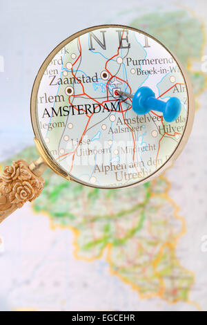 Blu Tack su la mappa del Benelux con lente di ingrandimento cercando in su Amsterdam, Olanda Foto Stock