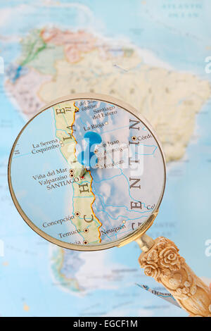 Blu Tack sulla mappa di Sud America con lente di ingrandimento cercando in su Santiago, il Campidoglio del Cile Foto Stock