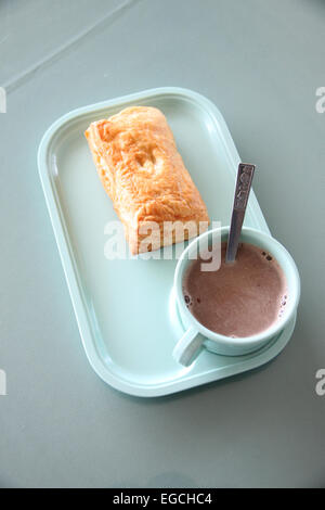 Patty e cioccolata calda in un piatto blu sul tavolo da pranzo. Foto Stock