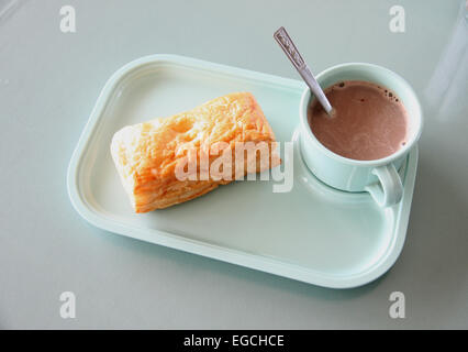 Patty e cioccolata calda in un piatto blu sul tavolo da pranzo. Foto Stock