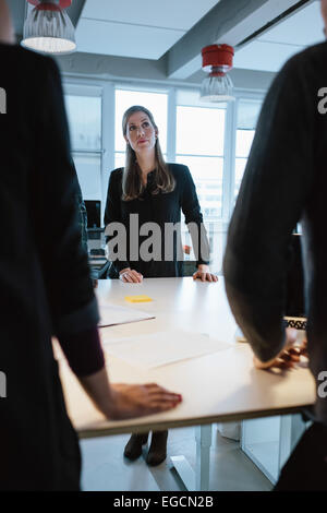 I giovani dirigenti di sesso femminile con i colleghi intorno a un tavolo in ufficio. La gente di affari durante la riunione. Foto Stock