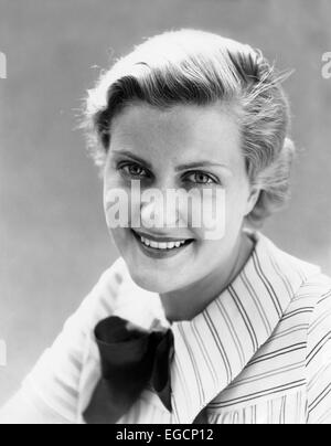 1930s FRECKLE fronte donna sorridente in telecamera indossando camicia a righe con fiocco in esterno Foto Stock